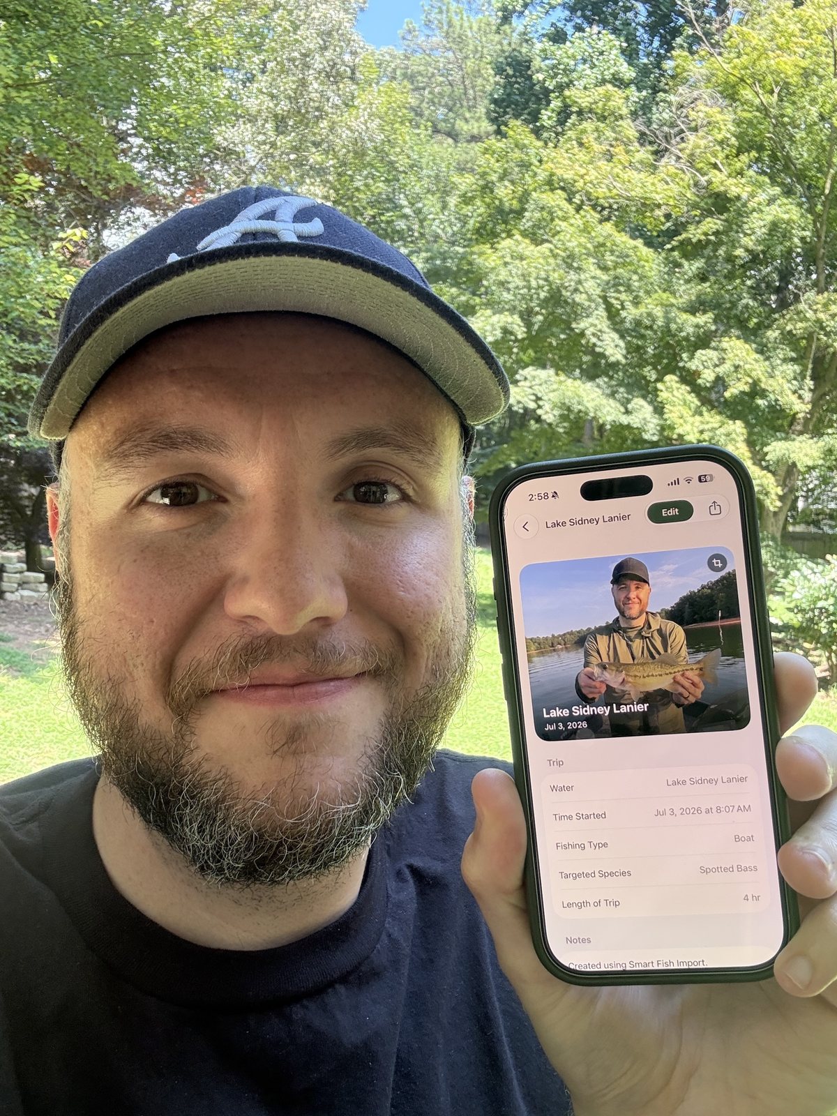 Shay Wade holding a phone showing a Fish Wizard fishing trip entry